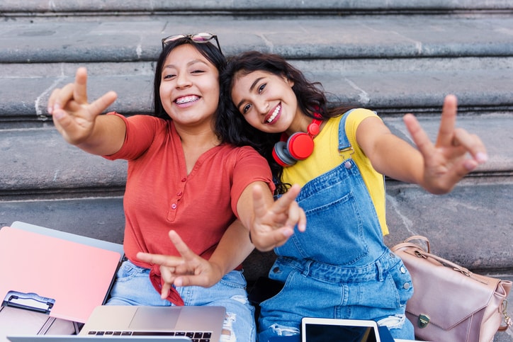 Two happy college students smiling on some steps.