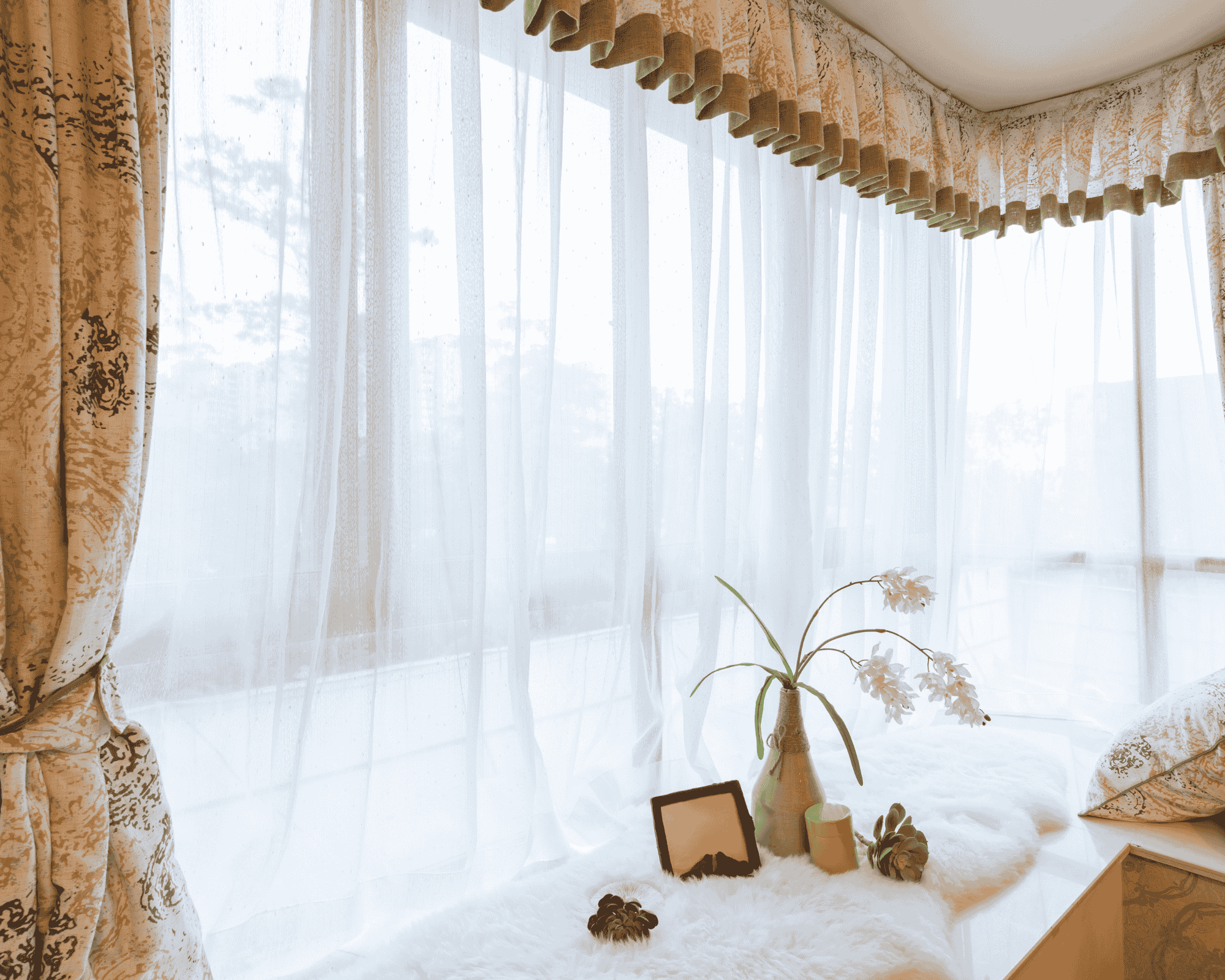 Classic patterned curtains with white sheers framing a cozy window seat with decorative items and city view