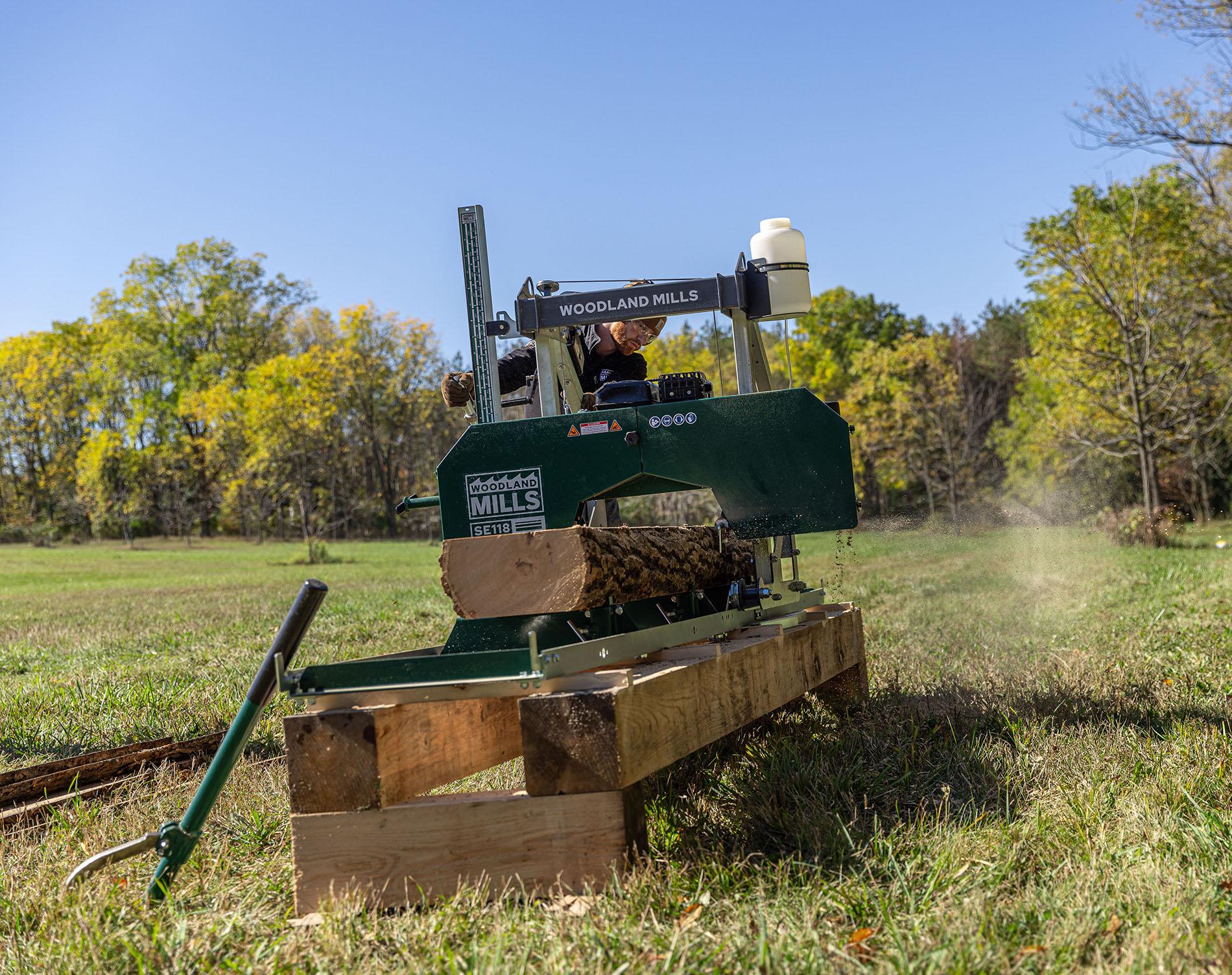 Un propriétaire foncier en train de scier une grume sur sa scierie portable Woodland Mills SE118. 