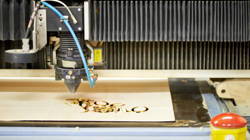 CO2 laser machines are cutting wooden brand label.