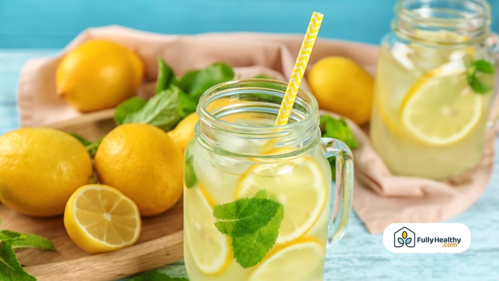Refreshing lemon water with mint in mason jar and whole lemons nearby