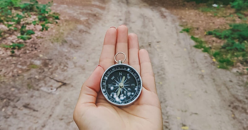 A person holding a compass on a path which represents behavior patters within the PULse Farmework.
