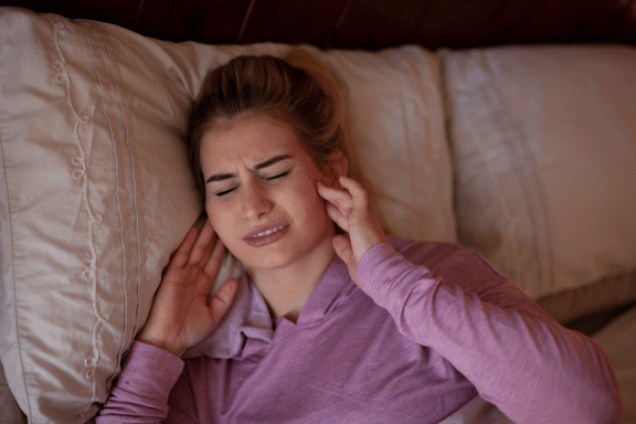 woman clenching her teeth with her hands on her jaw joints in discomfort