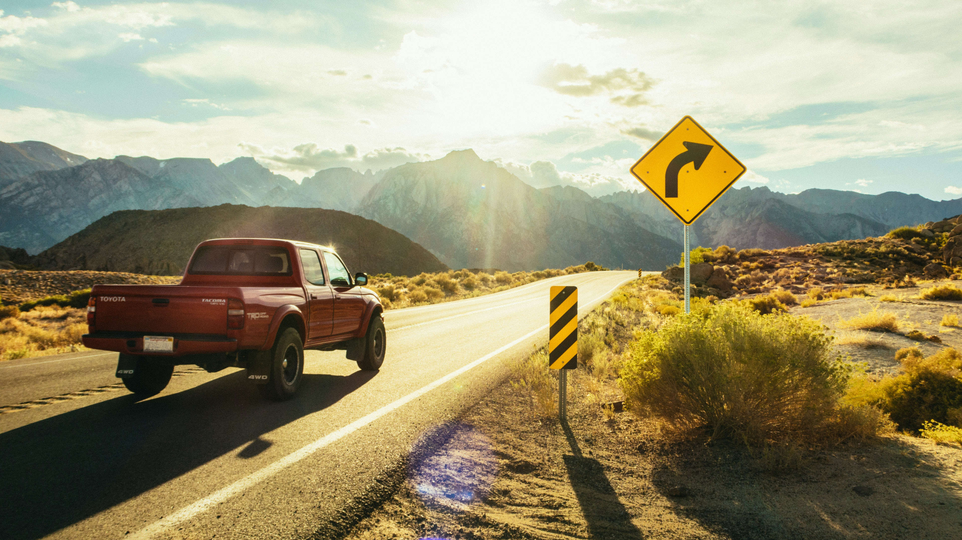 Picture of red pickup truck rounding a corner on a road