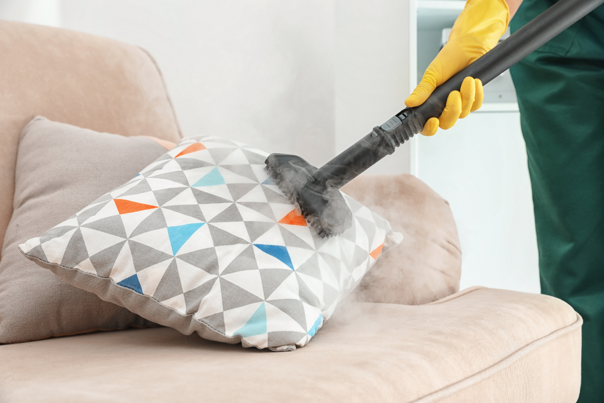 A couch with cushions being vacuumed and flipped, with protective covers visible