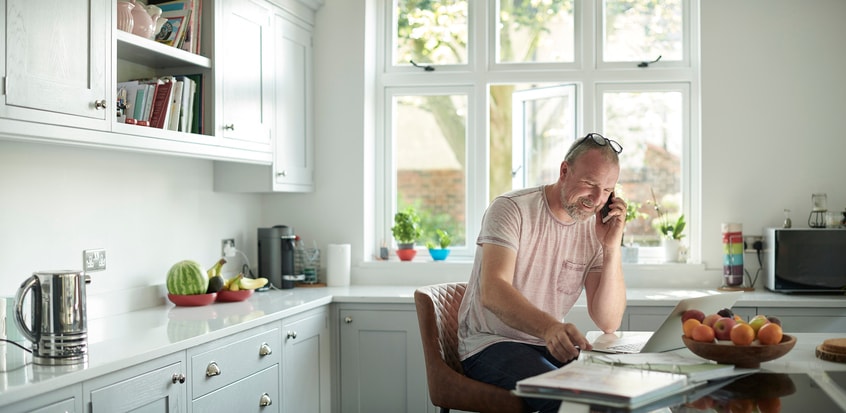 Man sitting in the kitchen talk on his cell.