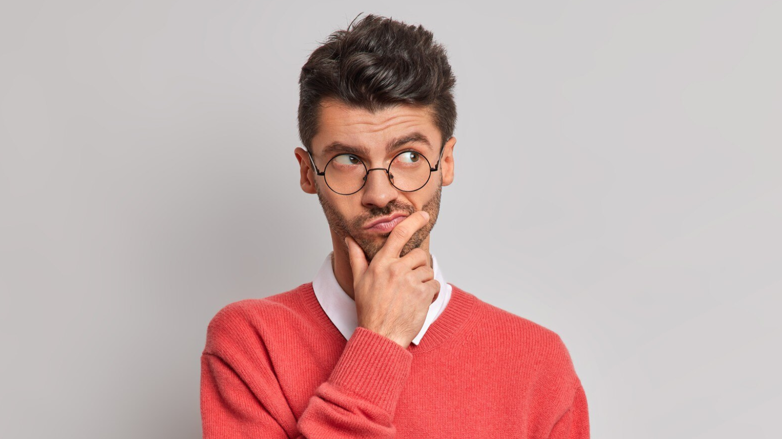 A man in glasses pauses in thought, hand on chin, looking off to the side—capturing the moment many business owners face when they’re wondering what exactly a POTS Replacement Solution is.