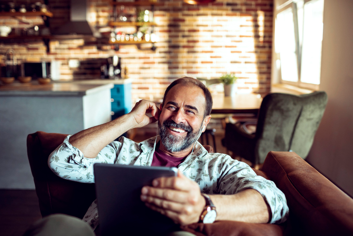 Man with a gray beard smiling and talking on a cell phone. 