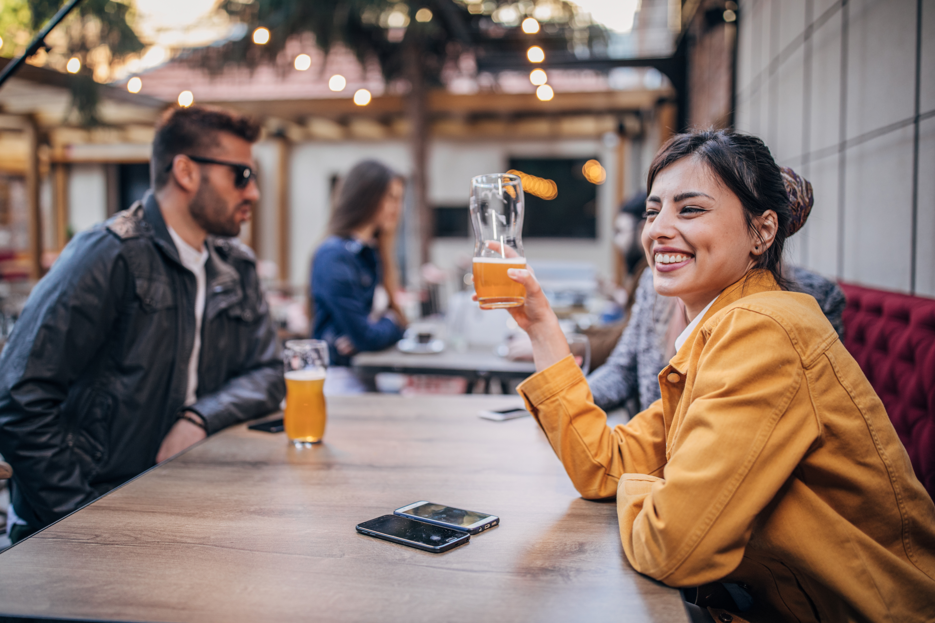 Group of young joyful friends having fun while talking and drinking beer in the Raleigh Beer Garden