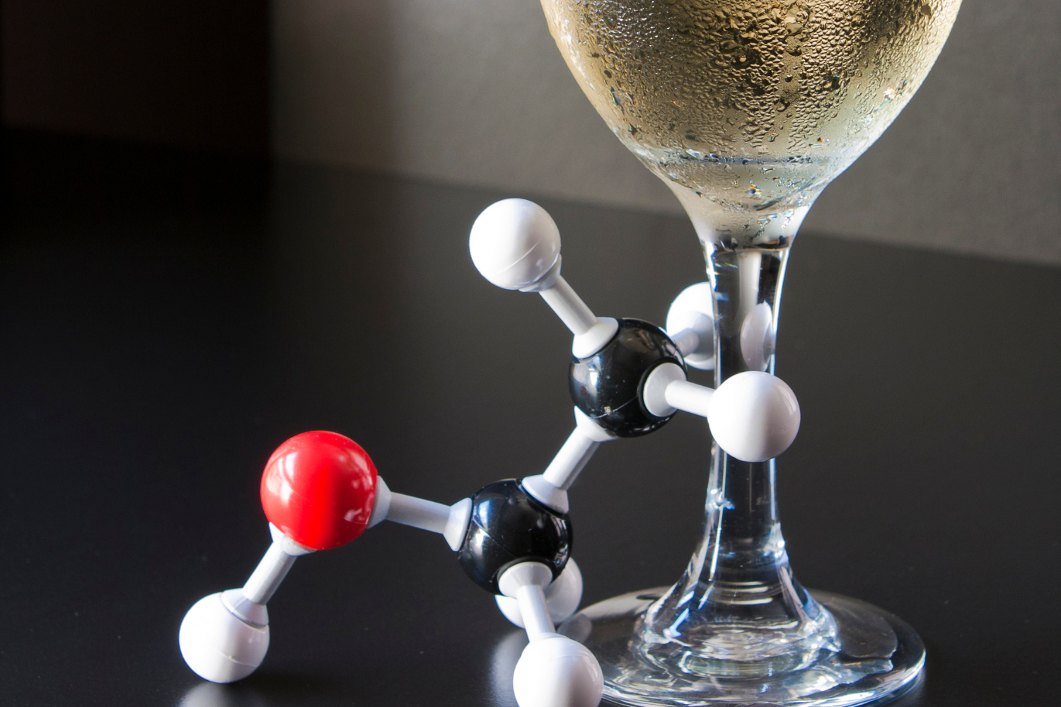 Ethanol molecule beside a glass of champagne.