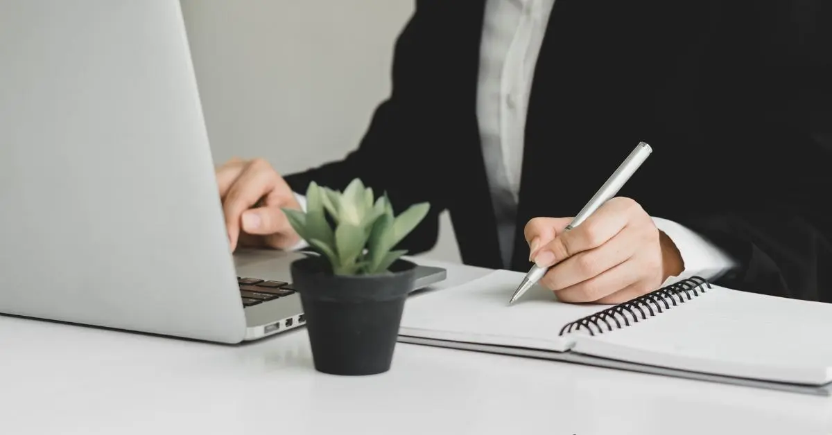 Business owner calculating non-deductible expenses for tax filing, using a laptop, and taking notes.