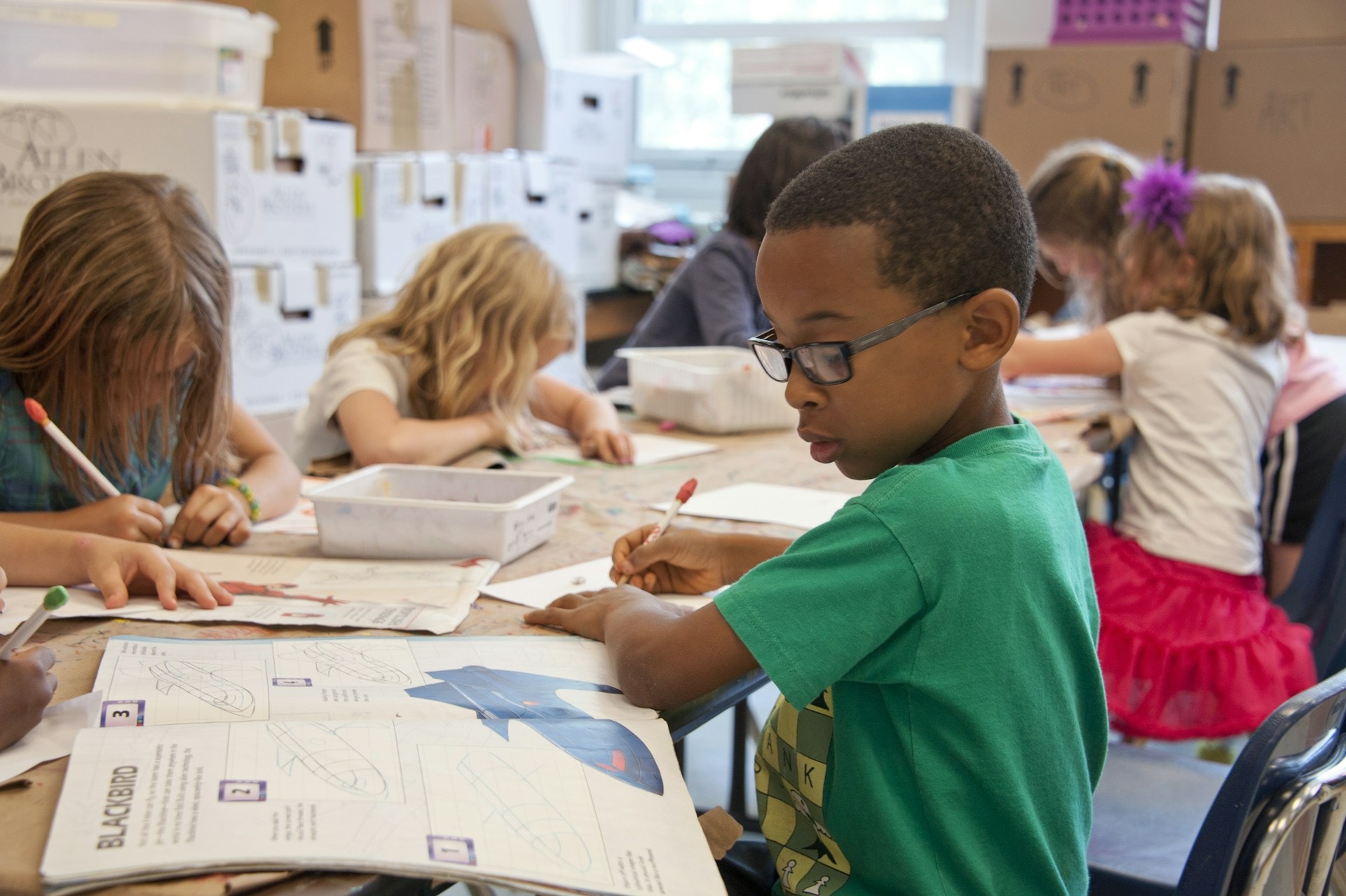 A child writing notes and looking at a school book