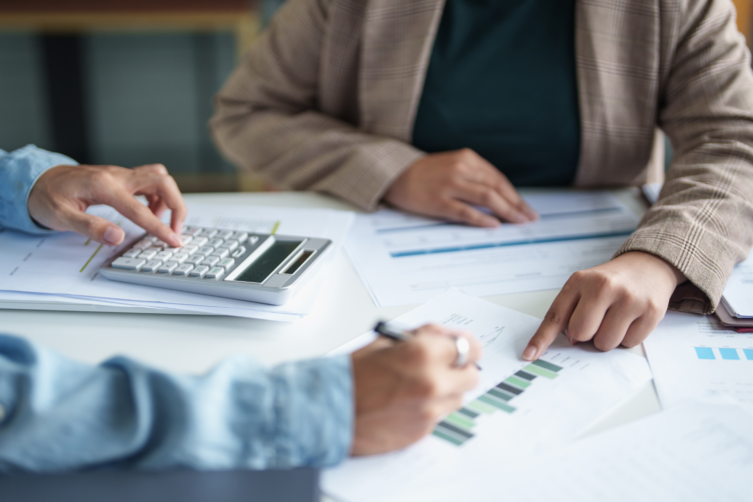People review financial documents and a calculator on a table.