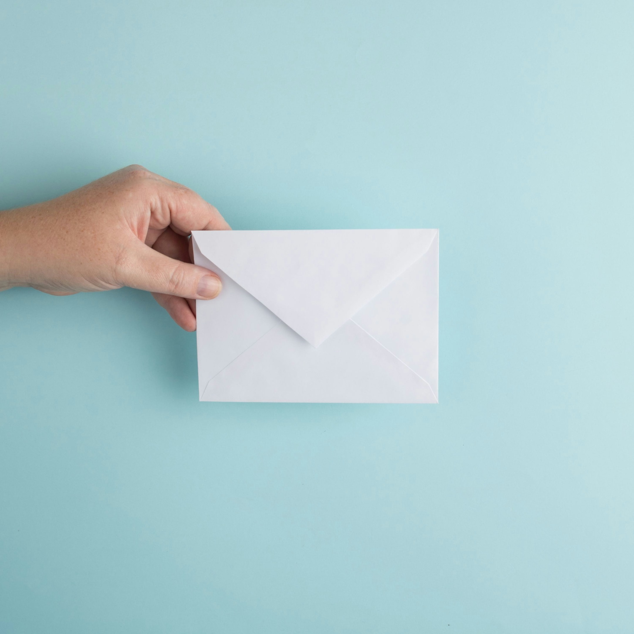 Real estate investor holds envelope that is being mailed to a motivated seller as part of a direct mail campaign. 