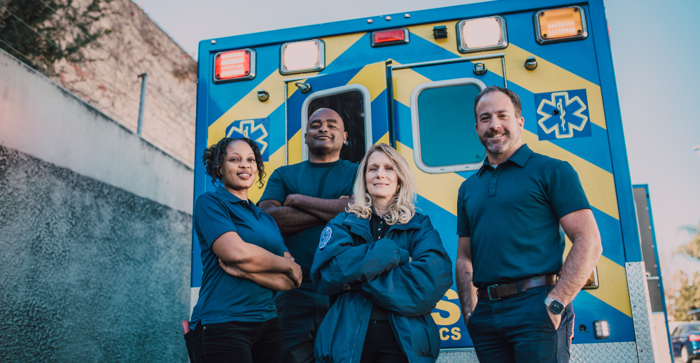 paramedics pose in front of their vehicle