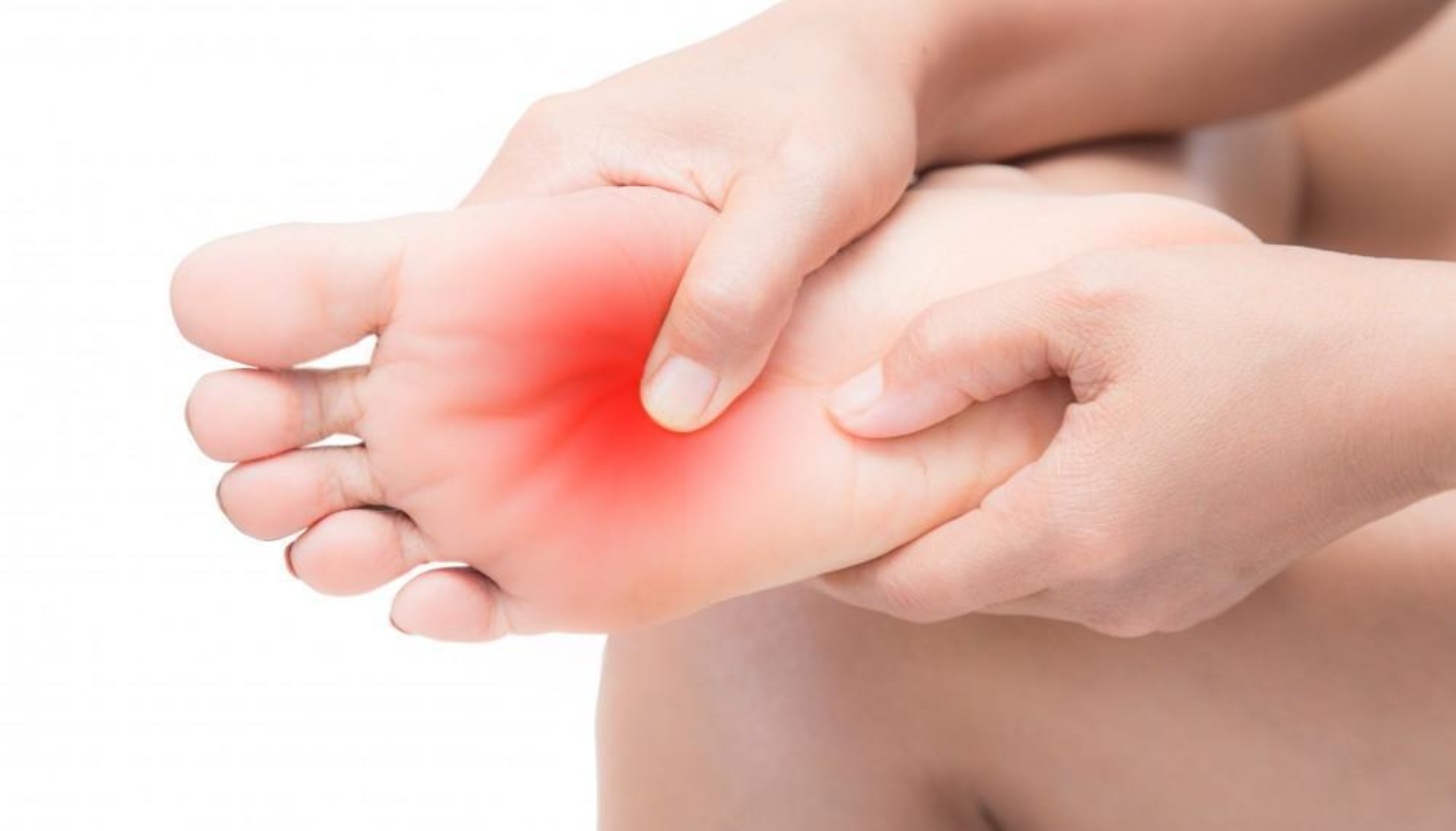 Hånd masserer fotsåle med synlig rødhet, som antyder smerte eller ubehag i foten.
