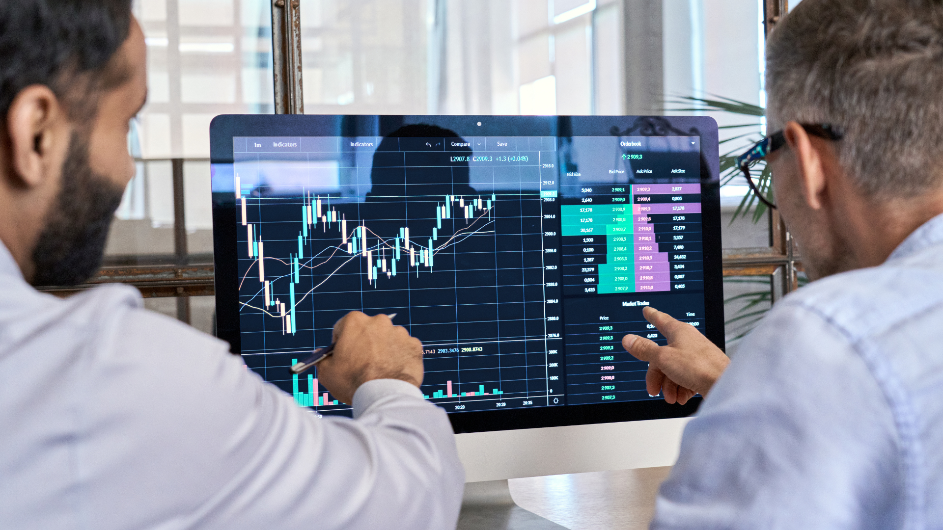 A person looking at a laptop with a stock chart on the screen