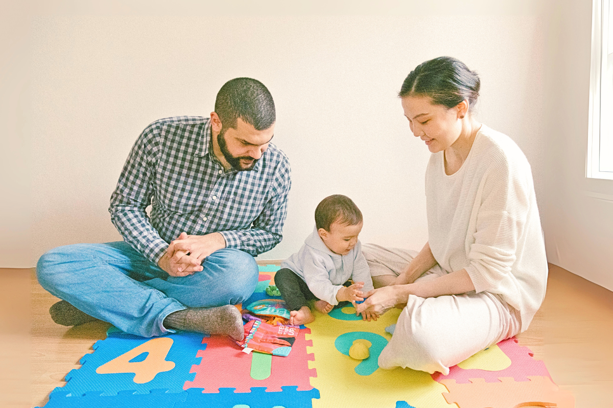 parents and baby sitting on mat playing