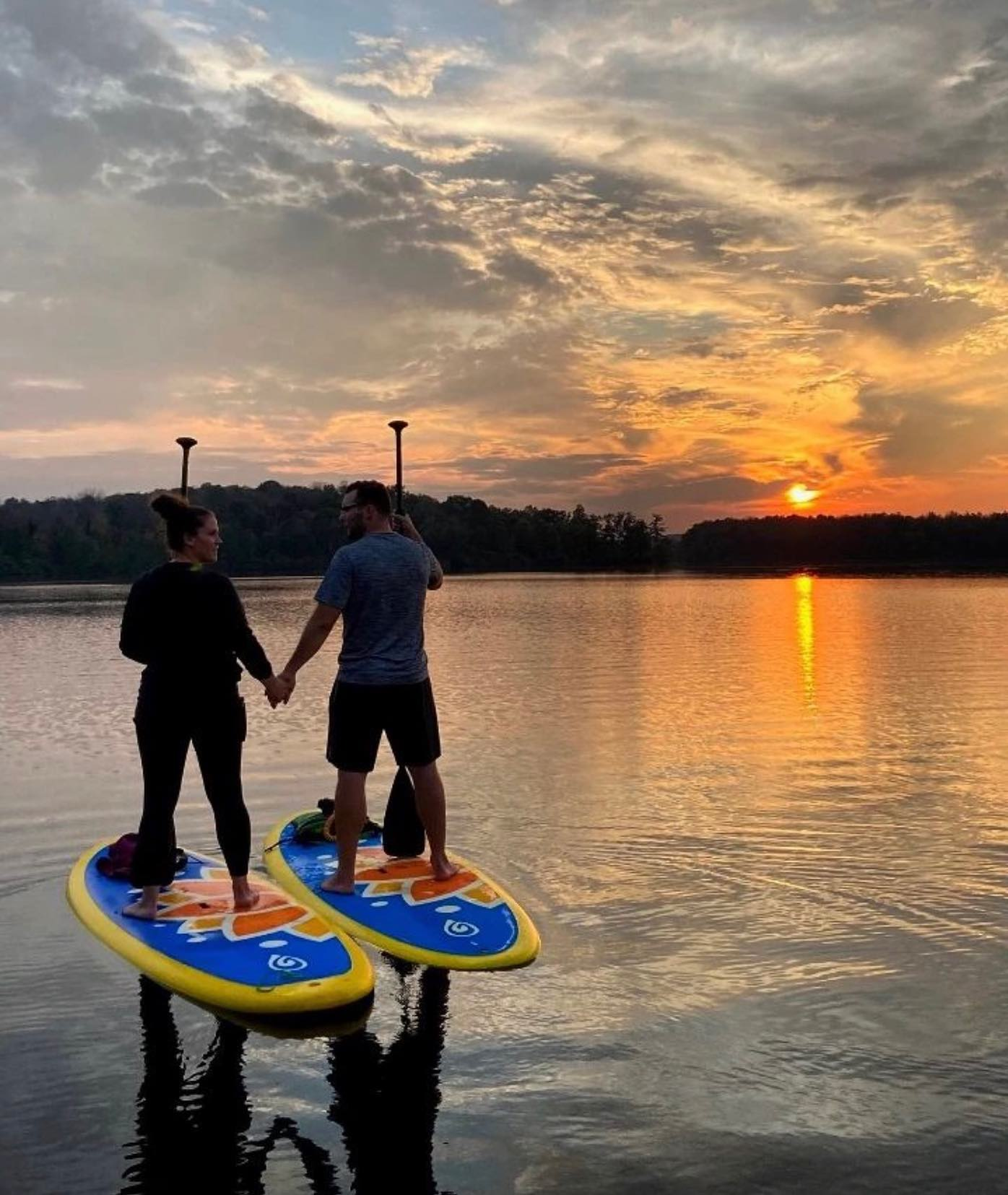 couple on paddle boards at the sun sets