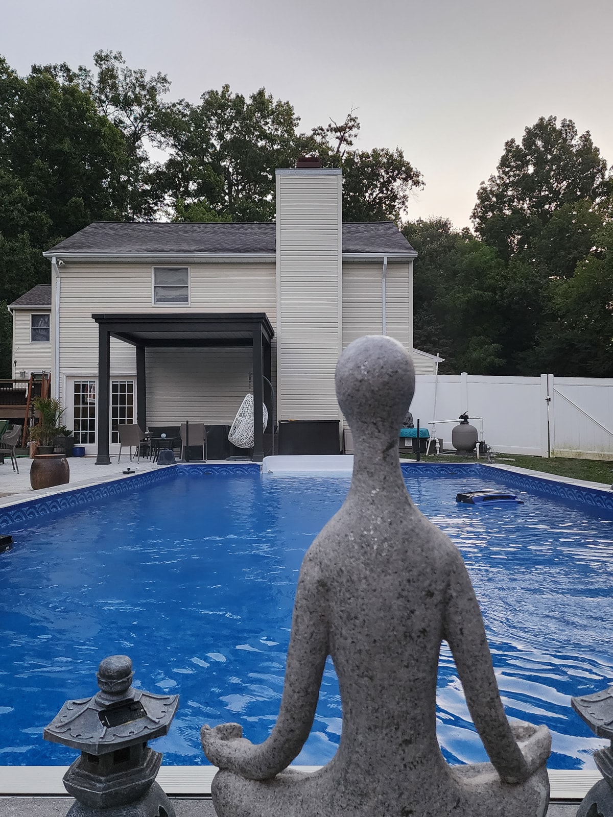 Poolside luxury pergola with peaceful statue.