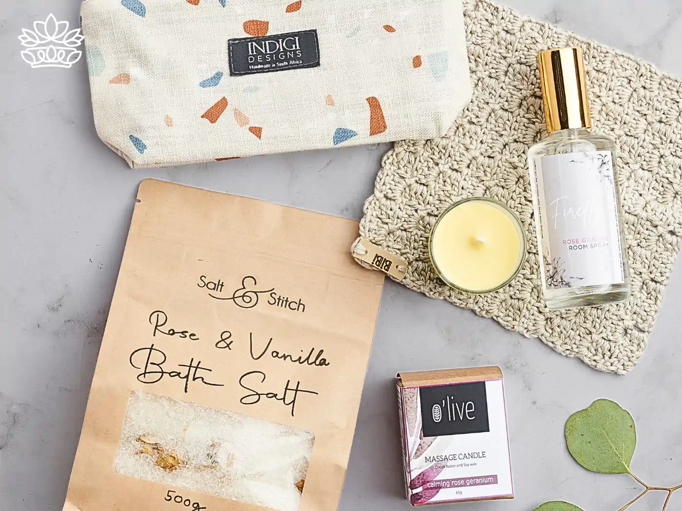 Wellness gift set including Rose & Vanilla bath salt, calming rose geranium massage candle, and a luxurious room spray, all thoughtfully presented on a knitted mat. Delivered with Heart. Fabulous Flowers and Gifts.