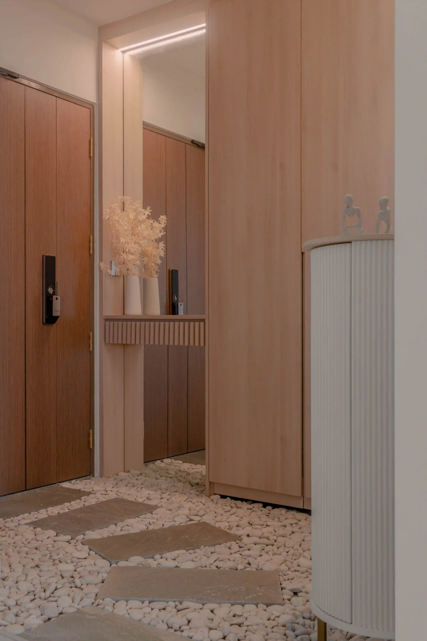 Warm wood HDB corridor featuring digital smart locks and pebble walkway