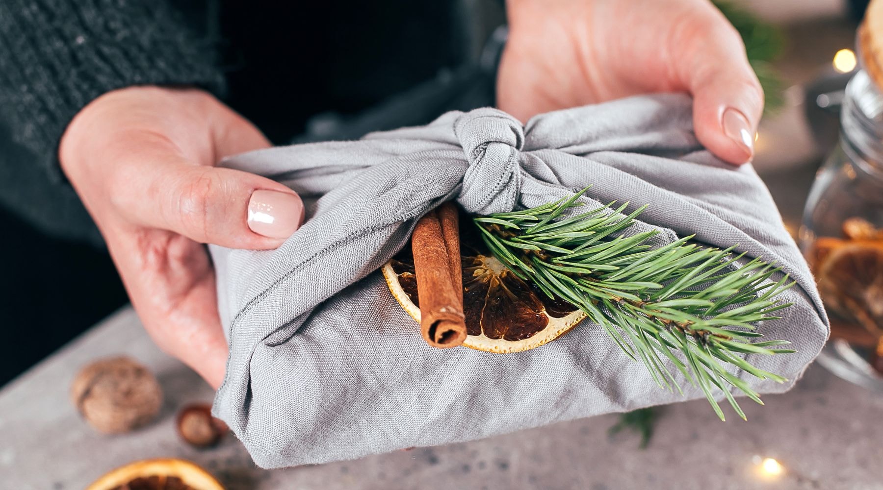 Grey cloth-wrapped gift adorned with cinnamon and rosemary.