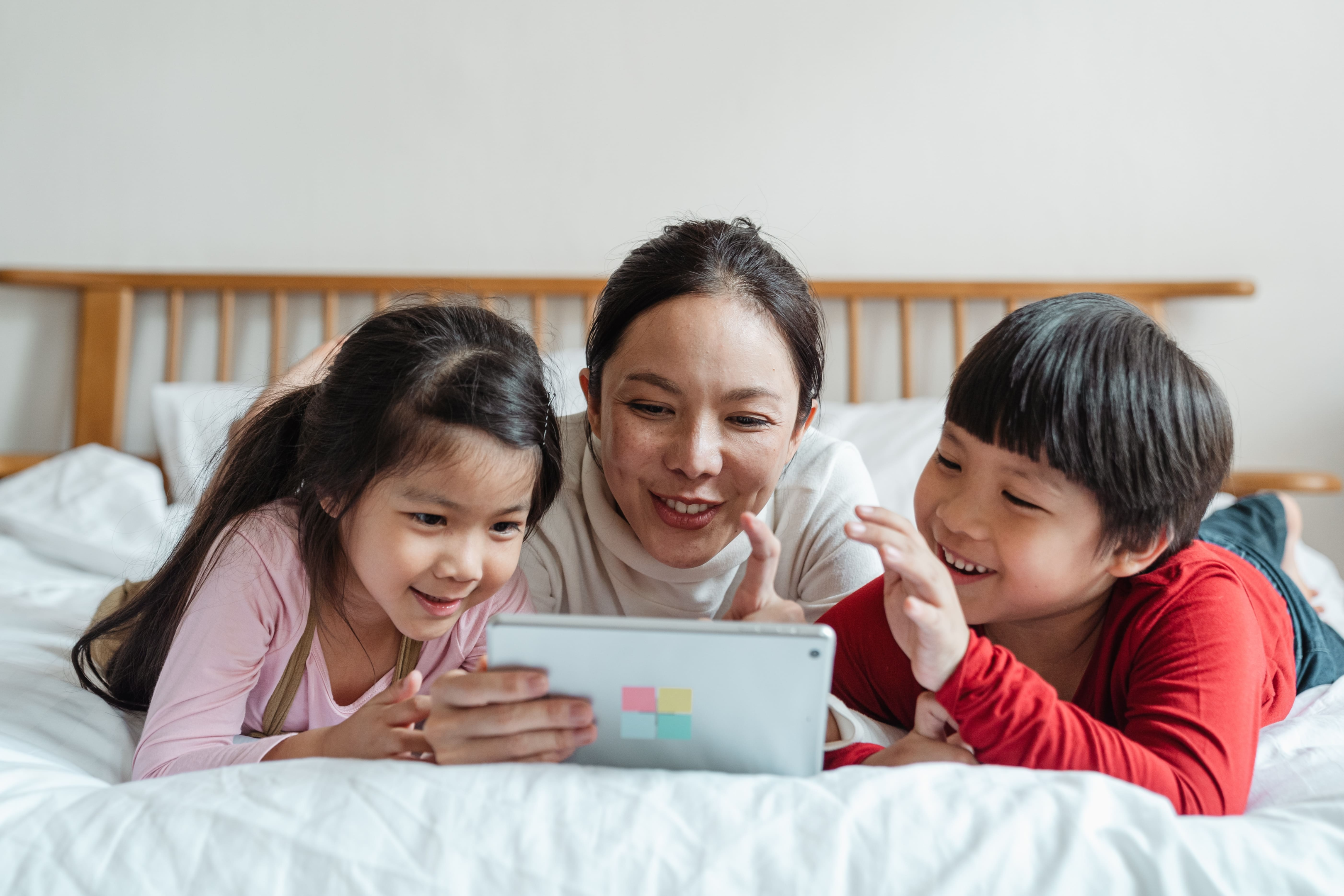Happy Asian mom with daughter and son on bed