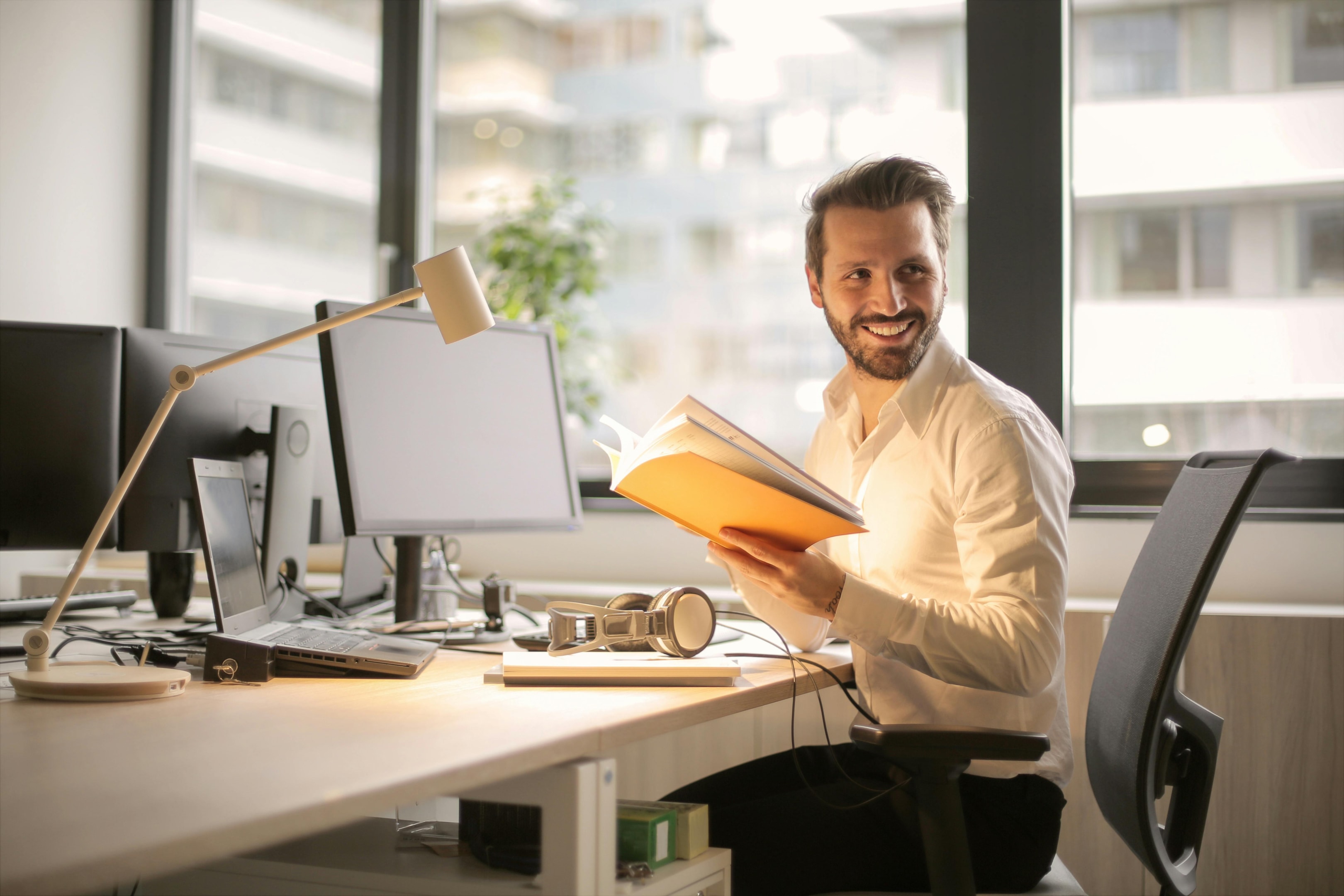 Financially secure man grinning while sitting on a chair in front of his desk. What does FI mean for him?