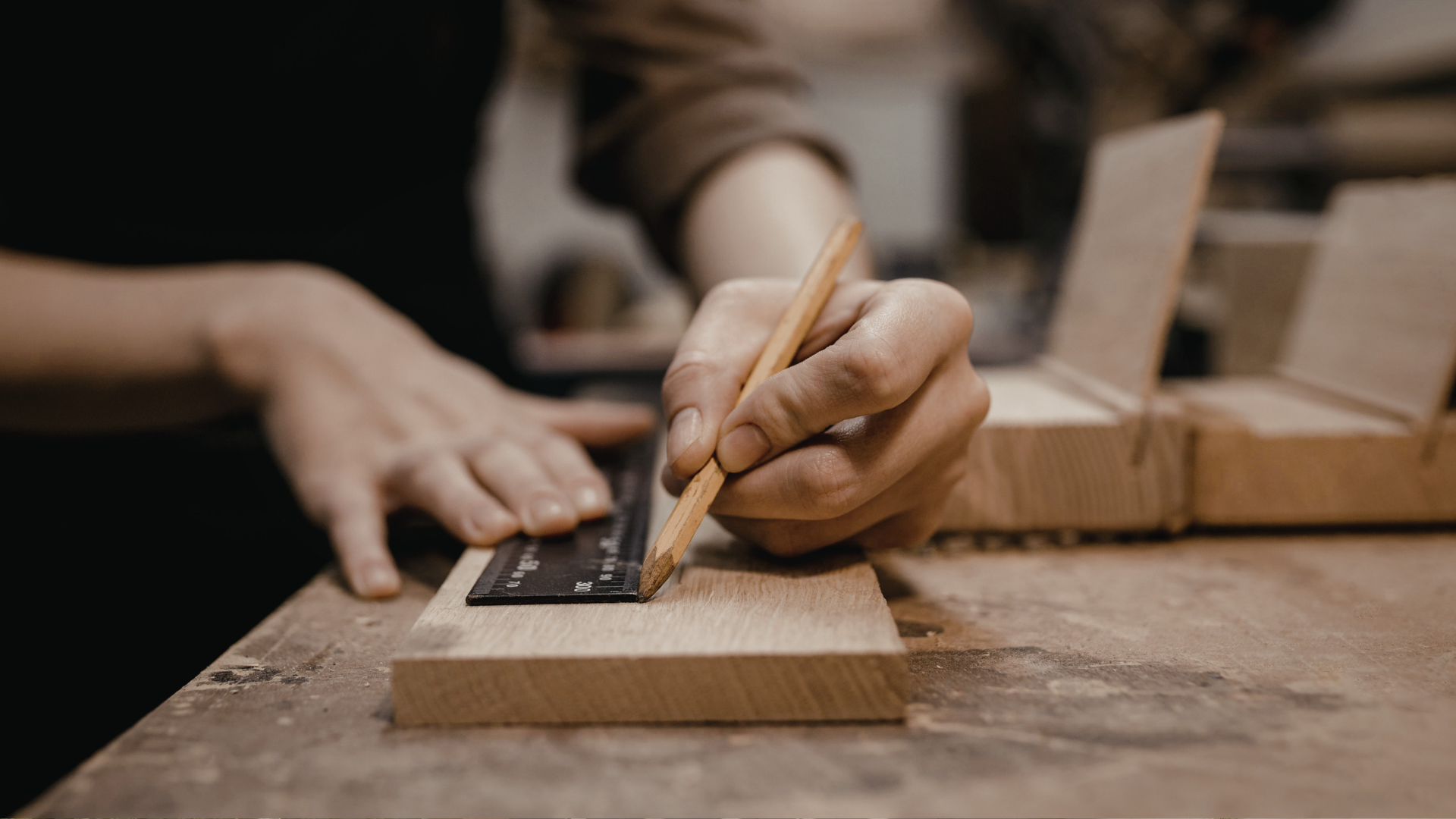 A man drawing a line on a piece of wood for a woodworking project.
