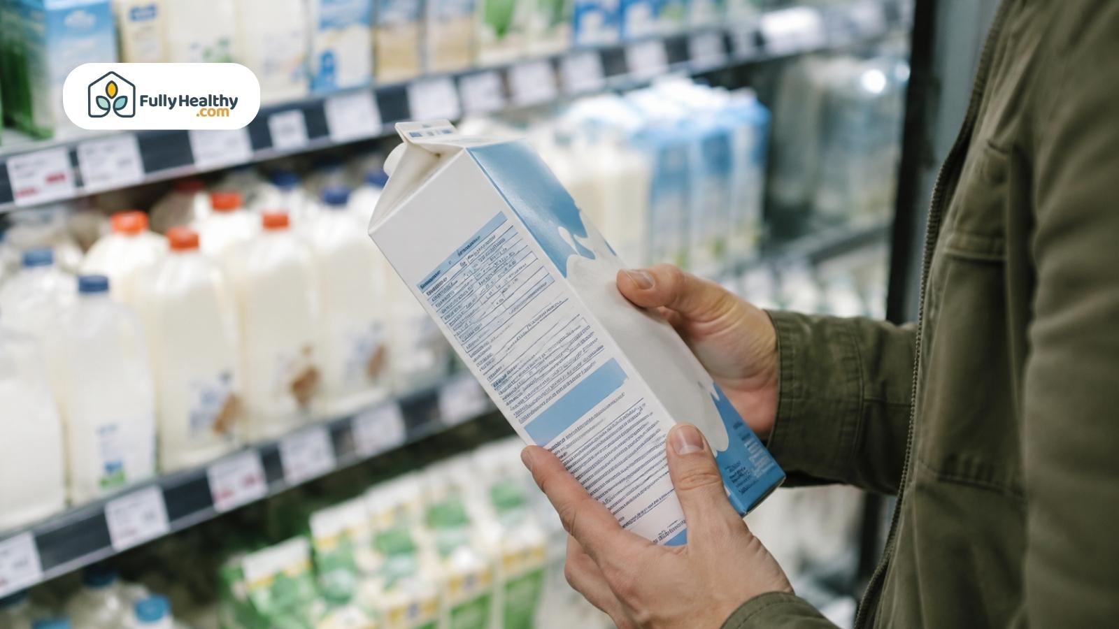 Shopper checking a milk carton nutrition label in a grocery dairy aisle