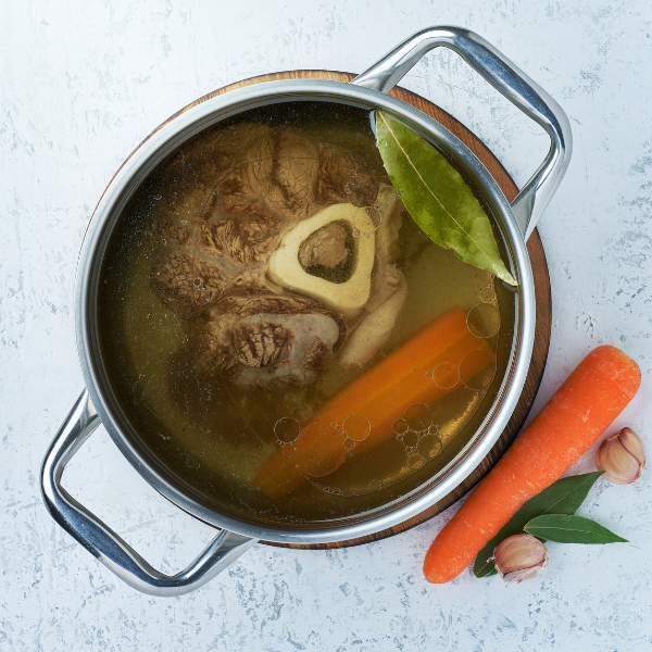 An image showing bone broth in a bowl with carrots for more flavor.