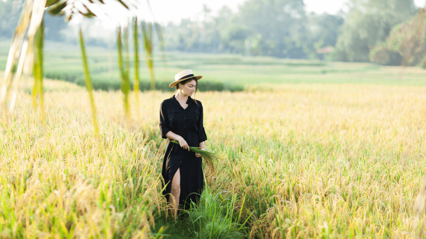 woman wearing a black dress and hat in a field