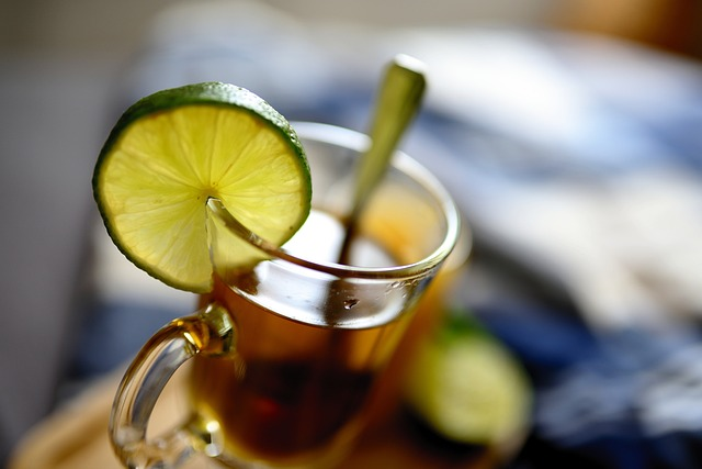 An image of a glass mug of herbal tea with a lime fruit slice on the rim.