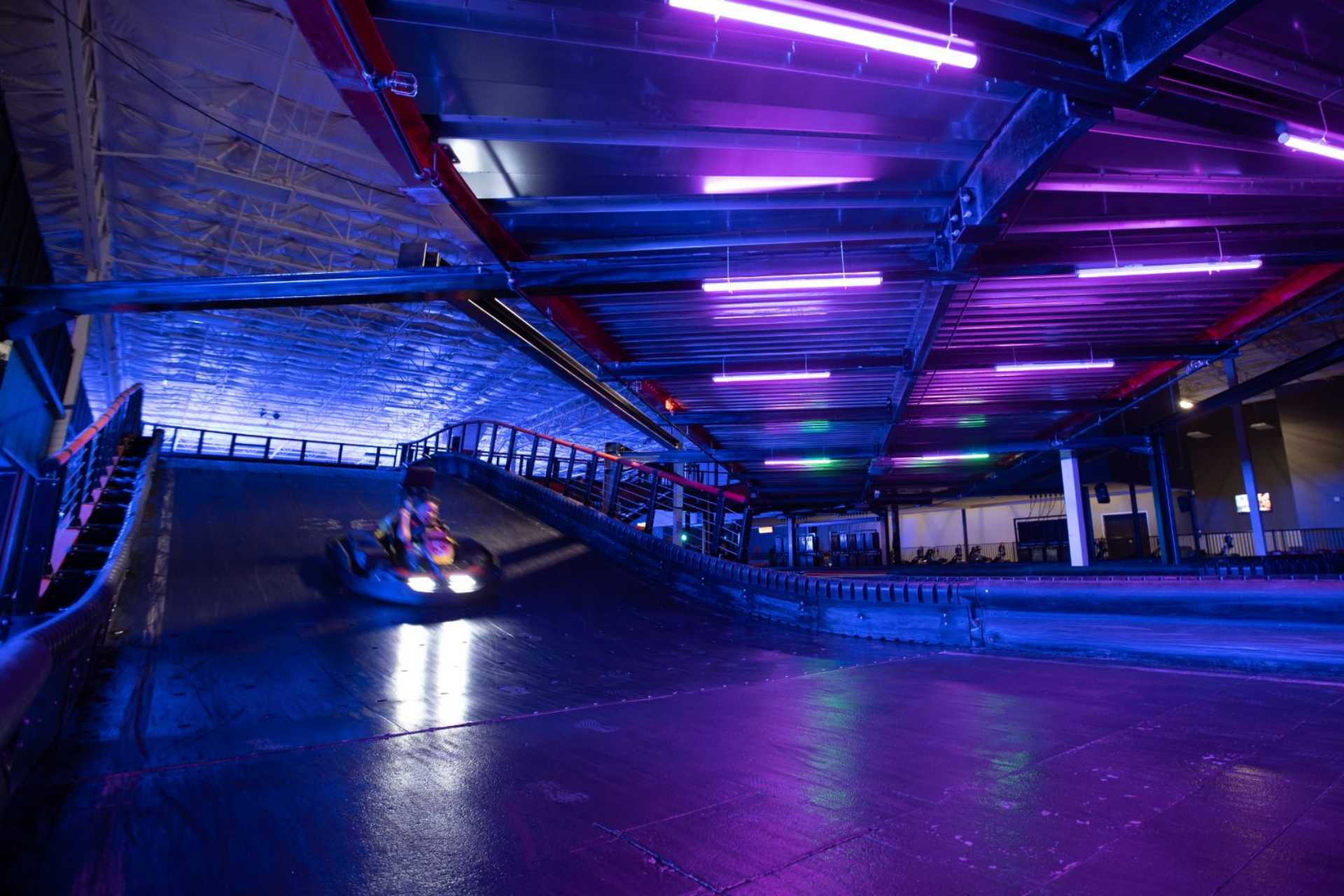 A go-kart races around the indoor track at Urban Air. The lighting makes the perfect backdrop for a fun adult birthday party. 