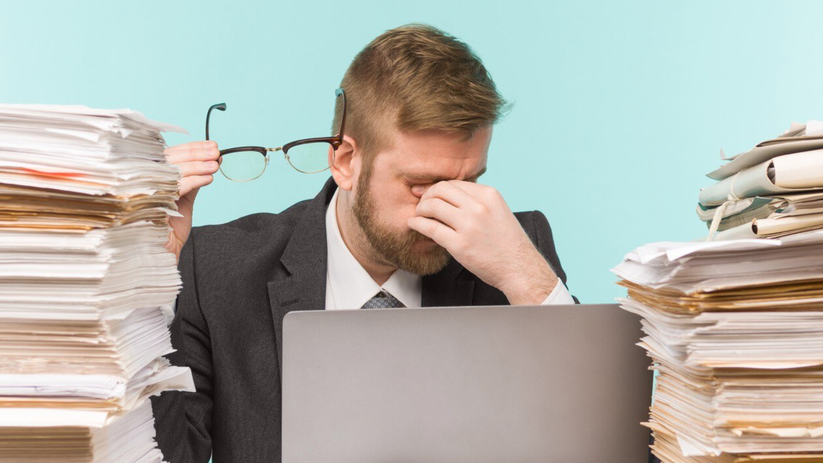 Overwhelmed man at laptop surrounded by paperwork, showing the administrative overhead of trying to figure out Operator Connect or Microsoft Direct Routing solo.