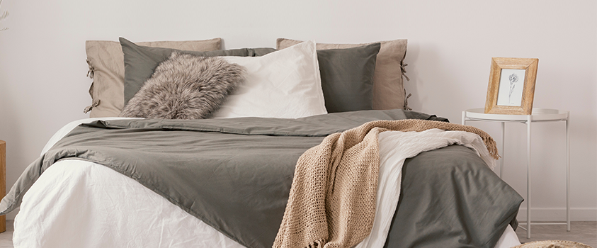A bed layered with several blankets and pillows of varying textures not only looks great but can help you sleep better.
