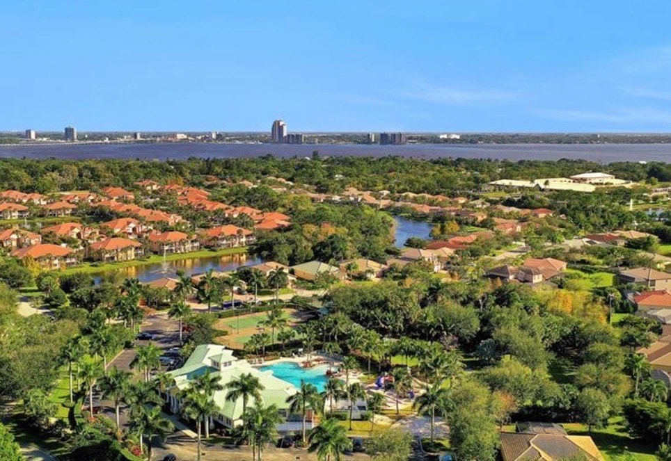 An aerial view of Moody River Estates in North Fort Myers showcases stunning waterfront homes along the Caloosahatchee River, with several boats docked at the community marina. This gated community features amenities such as swimming pools and tennis courts, making it an attractive option for buyers seeking single-family homes in Southwest Florida.