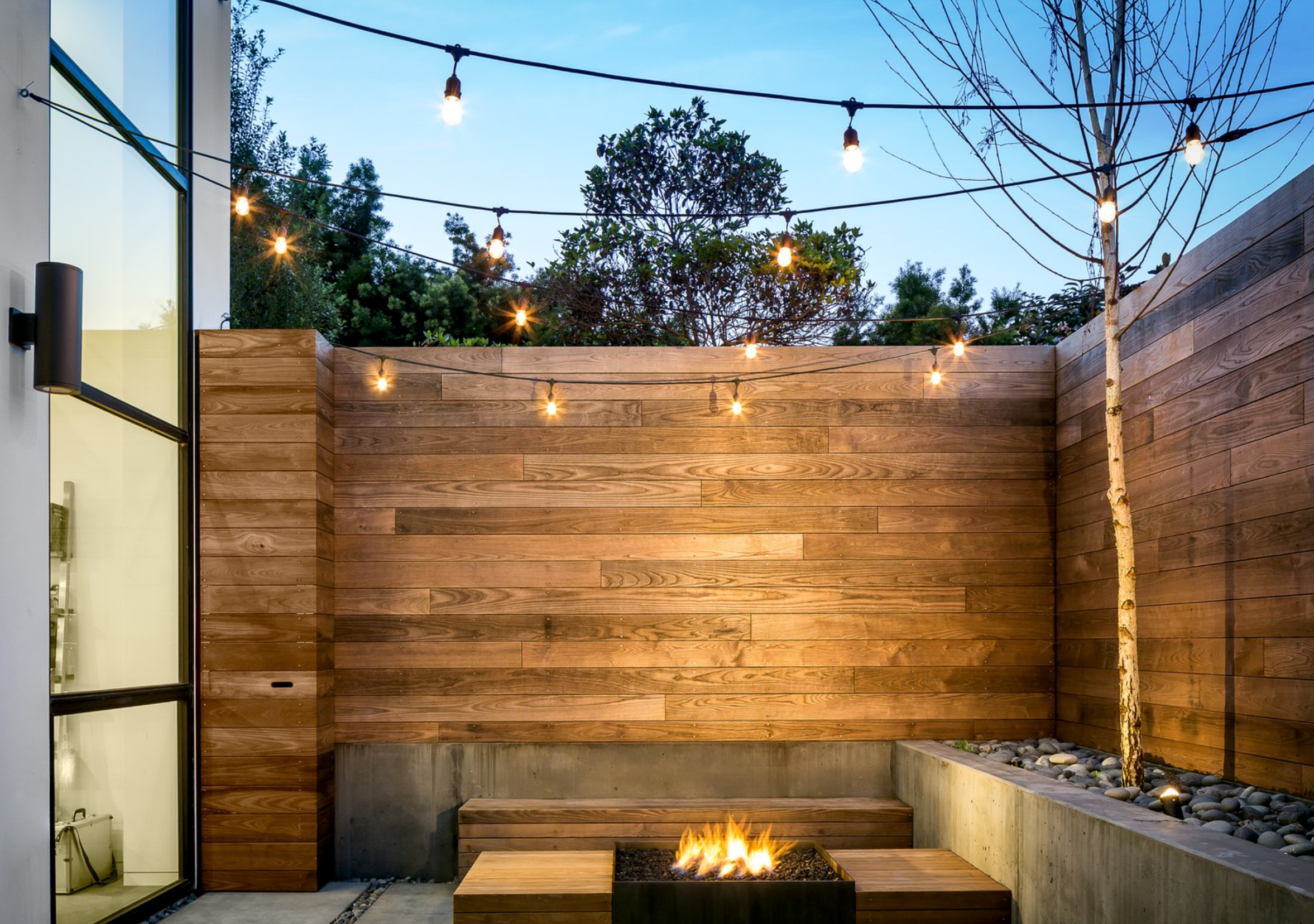 Wall lights on wooden fence with overhead bulbs