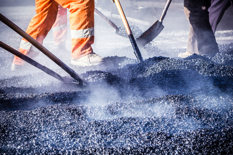 A picture of a hot mix asphalt being laid on a pavement