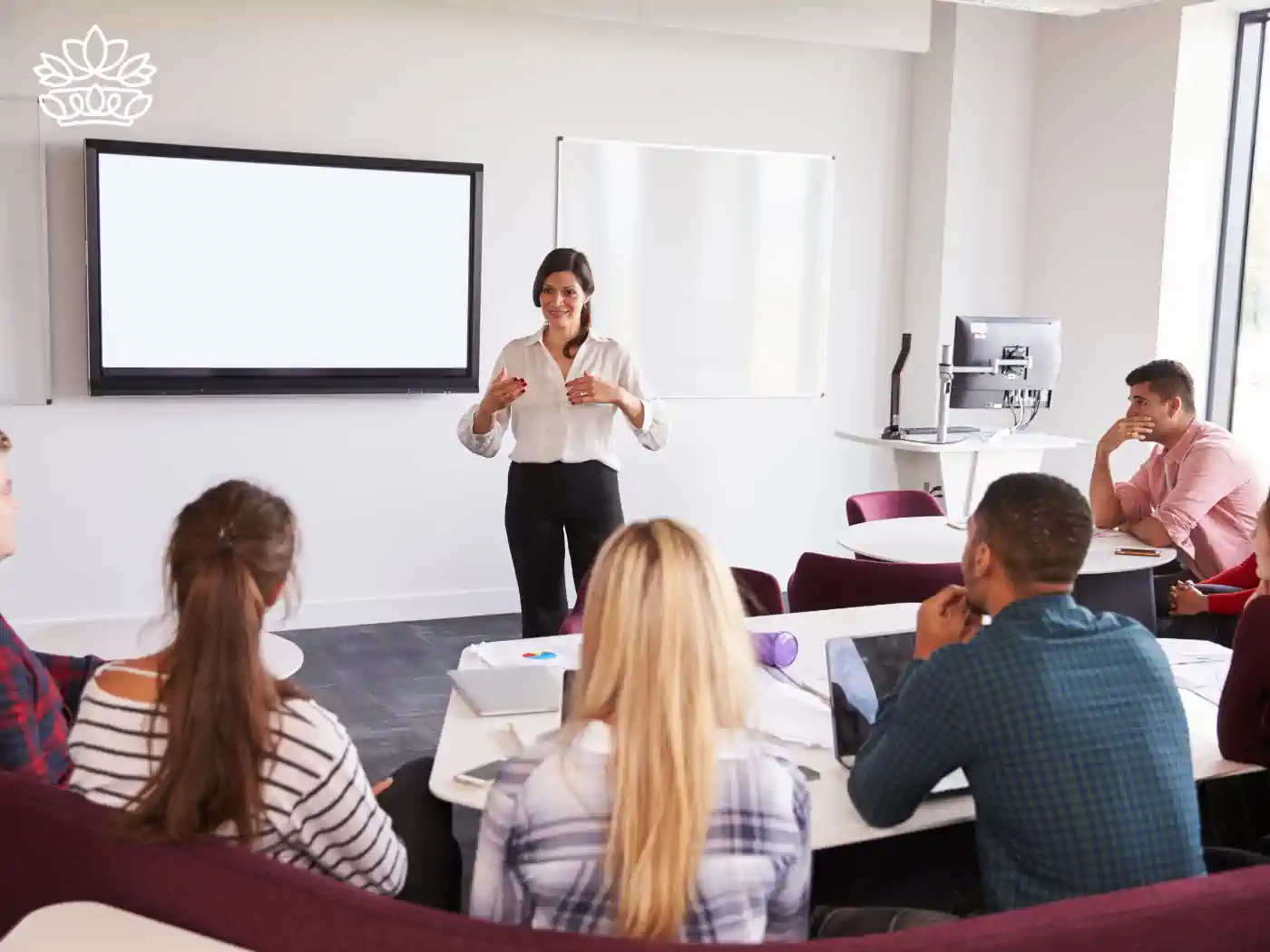 Professional development seminar with a female educator presenting to attentive adult learners in a modern classroom, fostering lifelong learning and growth, delivered with heart by Fabulous Flowers and Gifts