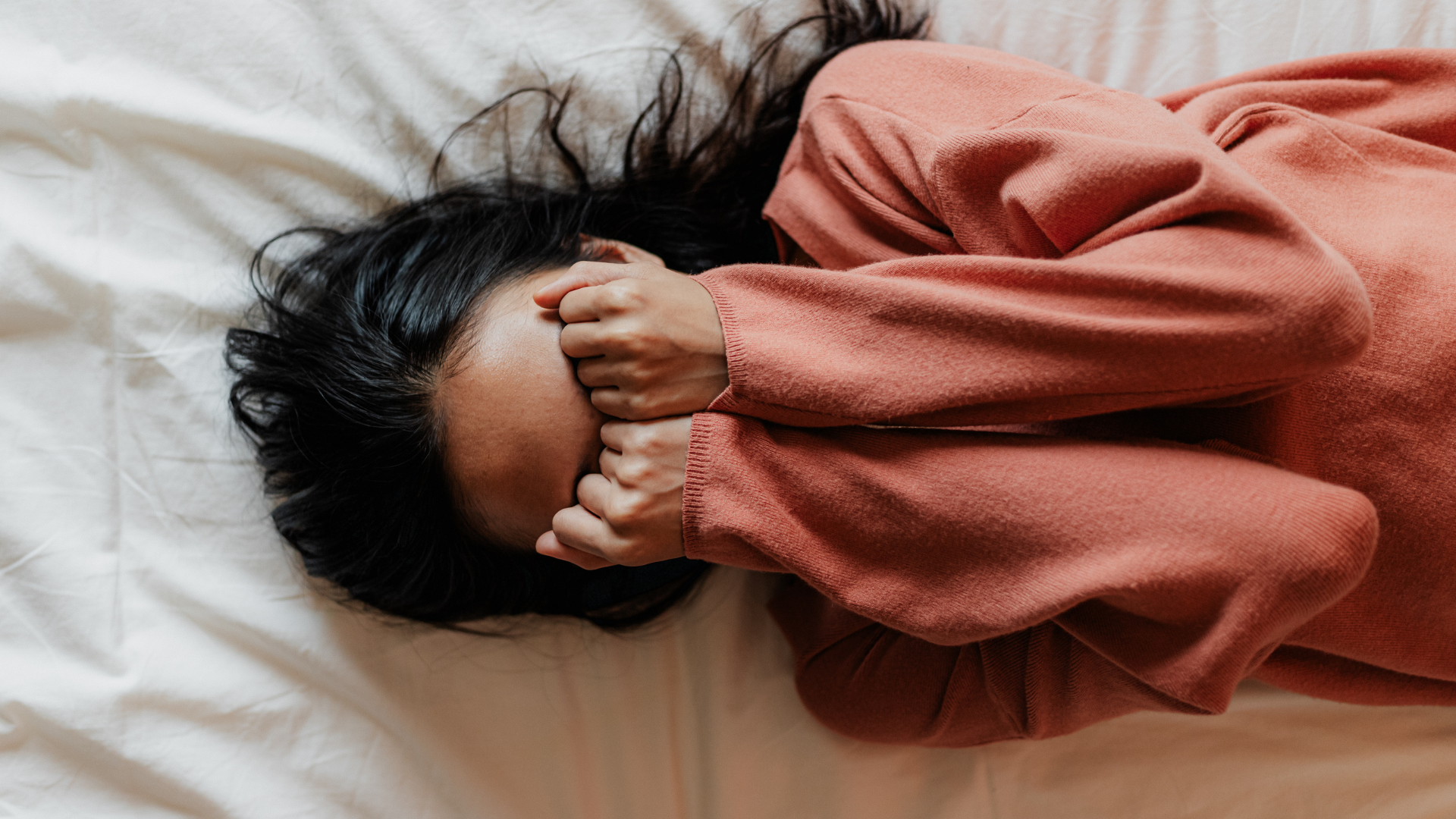 woman lying down with her head in her hands