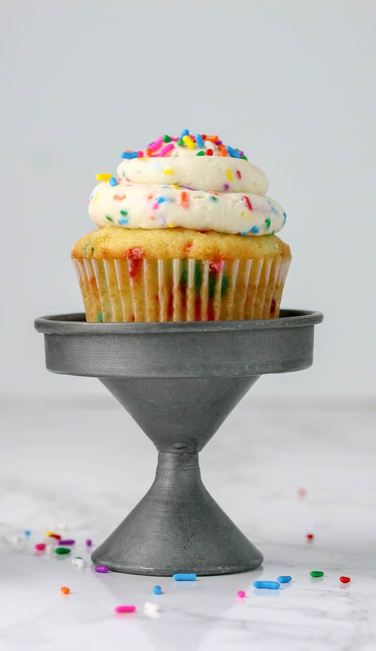 funfetti cupcake with sprinkles on top on a small cake stand