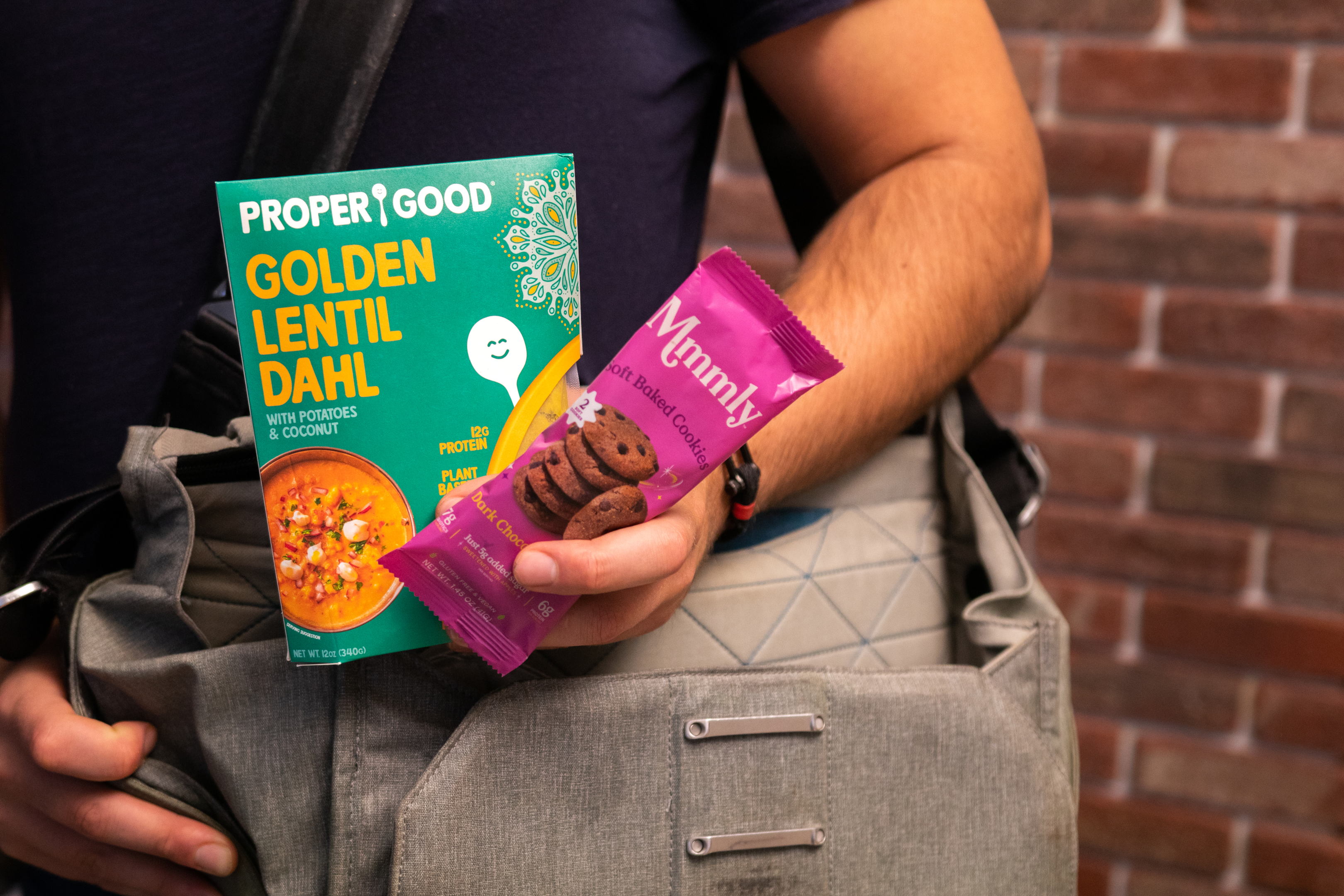 A person carrying Proper Good's Golden Lentil Dahl and Mmmly Cookies for a nutritious lunch