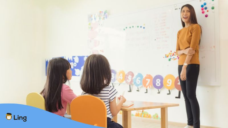 A Thai language tutor teaching her students about telling quantity in Thai nouns inside a well-lit classrom.