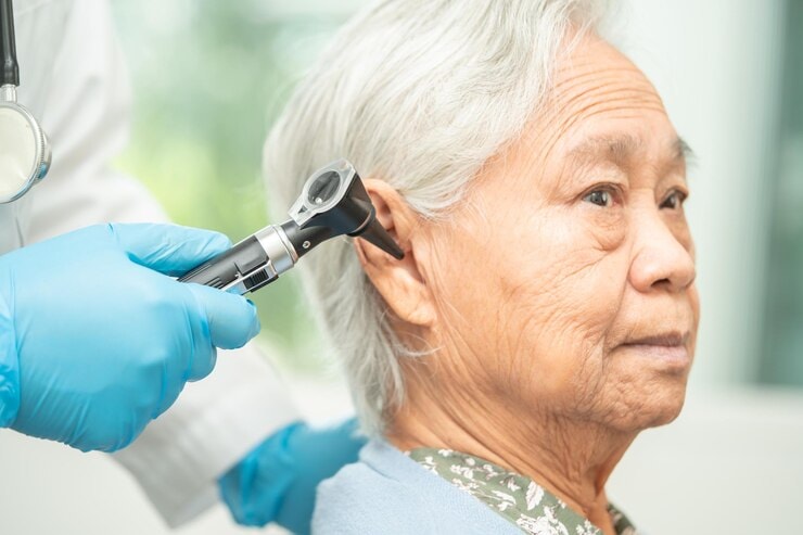 Doctor wearing gloves conducts a hearing test to an Asian elderly patient