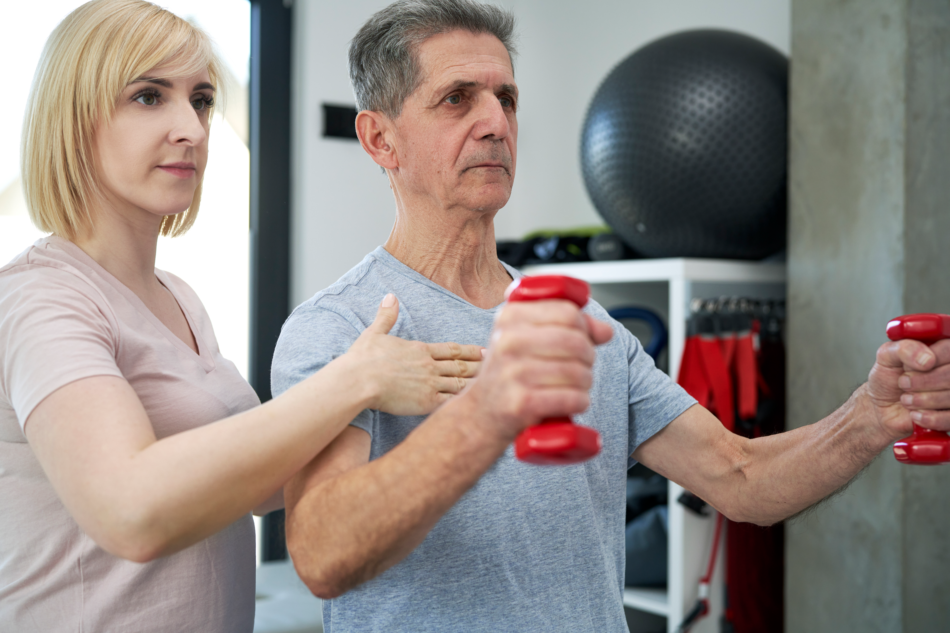 Image of a senior getting assistance at physical therapy; while there is some concernt that vibration therapy efficacy my be placebo effect, interventions like exercise and medication have been used for years.