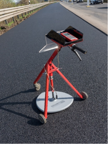 A worker using a tool to measure asphalt depth