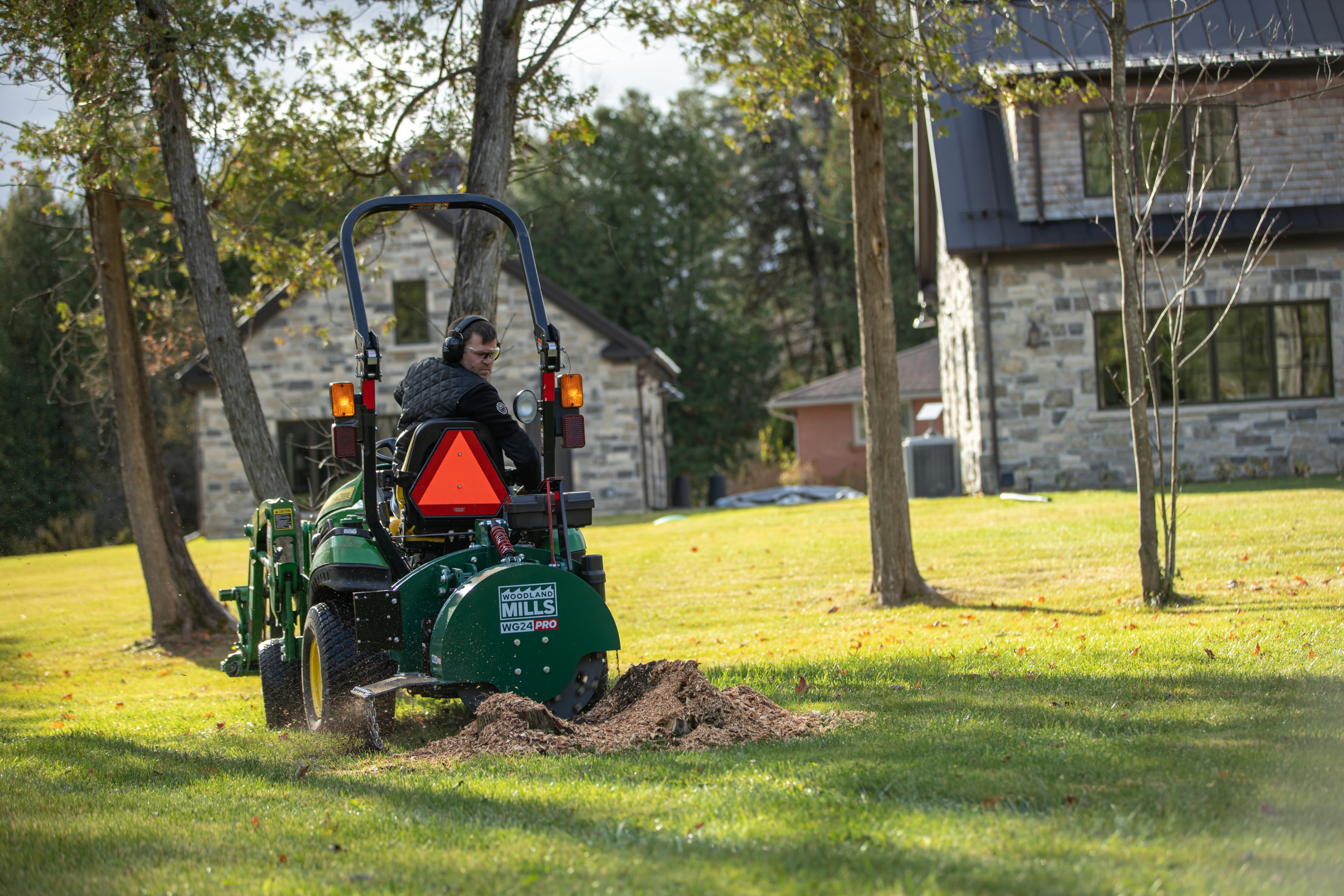 A tractor and stump grinder removing a stump. In open areas or tight spaces, if your tractor can get there, you can remove the stump.