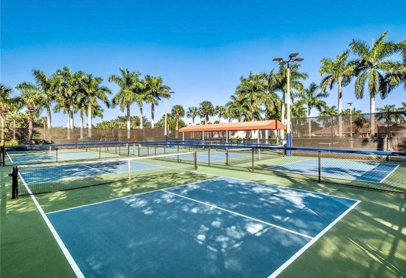 A scenic view of Corkscrew Road showcases tall palm trees and meticulously maintained landscaping, creating a welcoming entrance to the Bella Terra community in Estero, FL. This picturesque setting highlights the resort-style amenities and natural preserves that define the neighborhood.